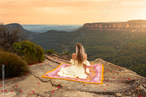 Woman on rug on mountain cliff with vsplendid iews