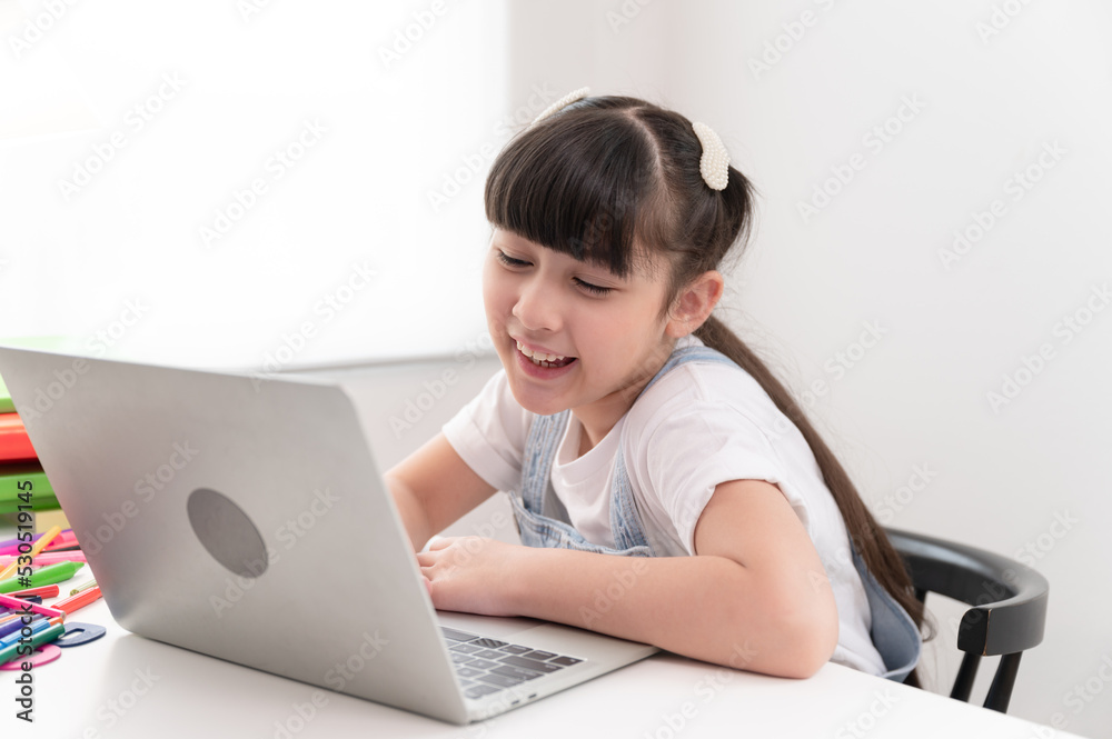 Portrait kids girl doing homework with notebook computer at home	