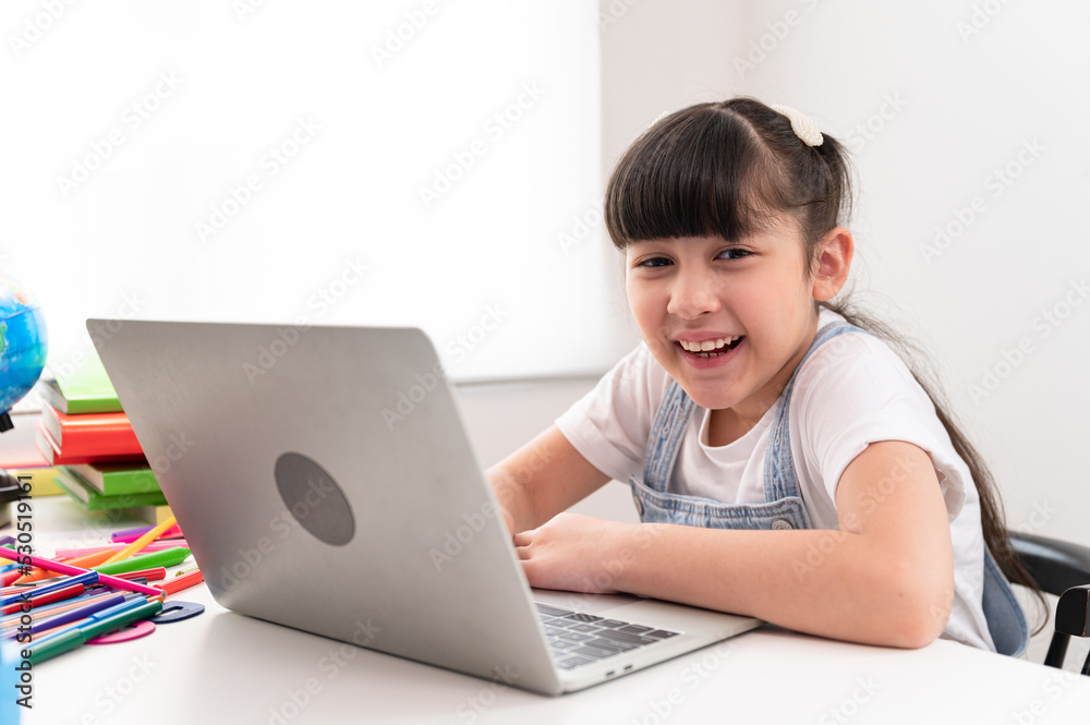 Portrait kids girl doing homework with notebook computer at home	