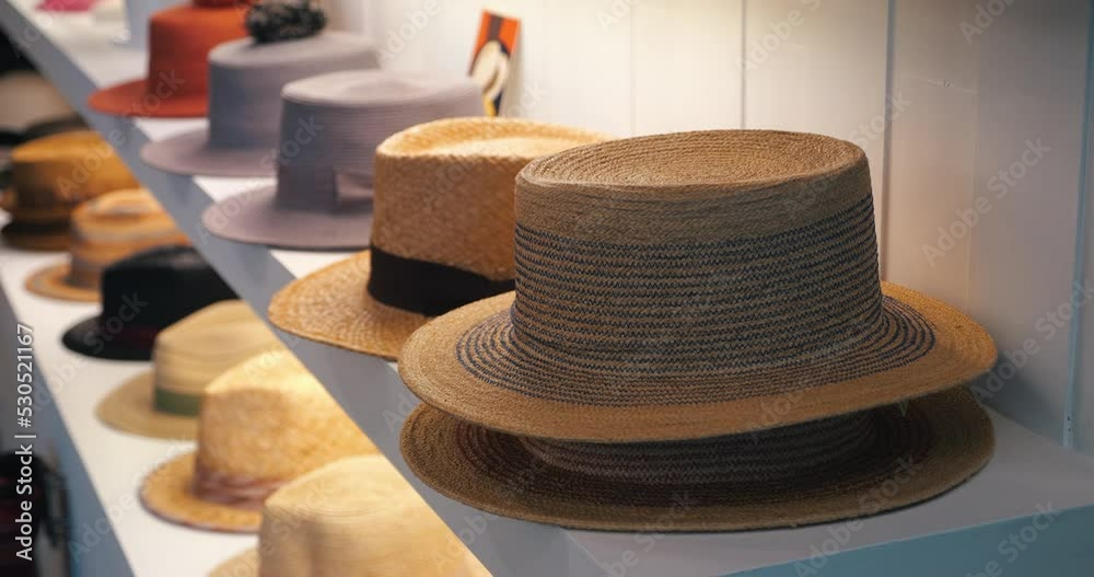 Steadicam shot: New seasonal collection of summer straw hats on shelves, display for sale in the headdress shopping store. Headwear. Headgear. Clothing store showcase with variety of caps and hats
