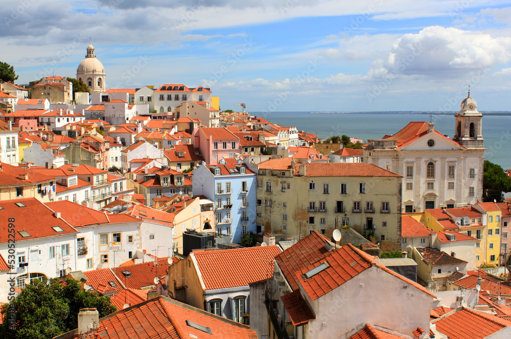 Exterior view of beautiful historical buildings, rooftops, and church towers in the old town of Lisbon, Portugal Europe. Colorful Mediterranean street in Alfama neighborhood.
