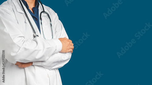 Midsection of a doctor in uniform standing with arms crossed on a blue background