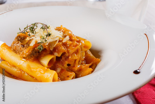 Piatto di pasta con sugo di genovese napoletana fatta con carne e cipolla e scaglie di parmigiano servito in un ristorante 