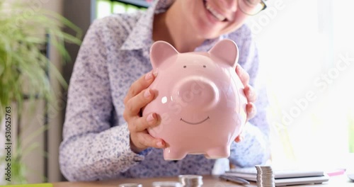 Emotionally joyful happy woman stroking and shaking piggy bank
