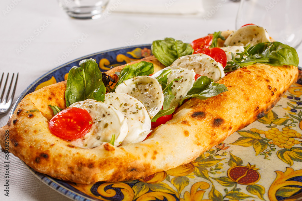 Base di pizza napoletana con sopra mozzarella di bufala, pomodori rossi