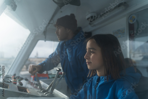 Fotografie, Obraz Man and children manning a ship from the control cabin