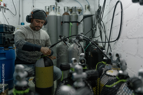 Man refilling oxygen tanks for diving indoors