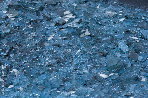 Shattered Glass. Background as broken pieces or crocks of white glass on the ground outdoors. Pine needles between glass pieces.