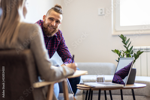 Female psychologist talking to young man during session.