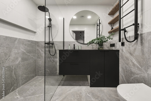 Wallpaper Mural Modern minimalistic bathroom interior design with grey stone tiles, black furniture, eucalyptus in glass vase, round mirror