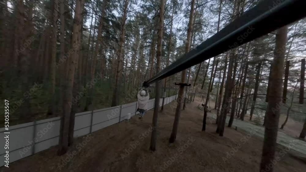 Flight along an zipline track with girl in an amusement park in the forest among the trees. Evening. Unusual FPV drone view.
Flight along an zipline track with girl in an amusement park in the forest among the trees. Evening. Unusual FPV drone view.