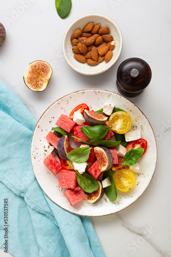 Overhead view of summer food salad tomatoes fig watermelon on light surface