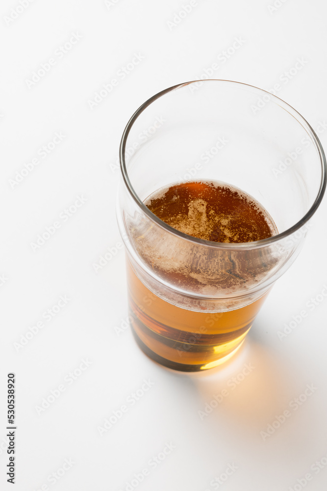 Overhead image of half full pint glass of lager beer, with copy space on white background Overhead image of half full pint glass of lager beer, with copy space on white background