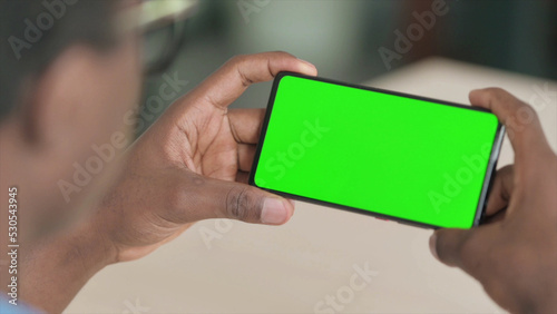 Close Up of Young African Man Watching Smartphone with Chroma Screen