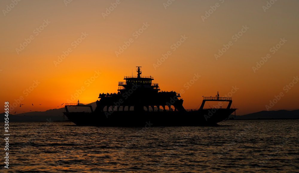 The silhouette of a ferry on the sea at sunset