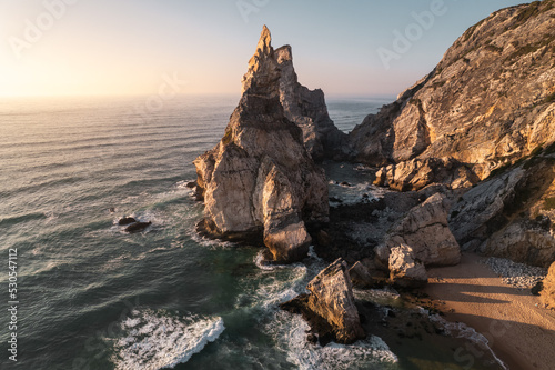 Rock formation near waving sea at sunset
