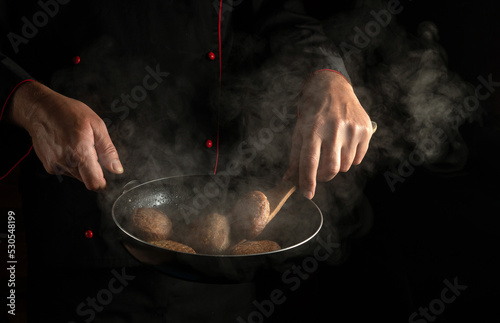 Fototapeta Naklejka Na Ścianę i Meble -  Cooking beef or pork cutlets in a hot pan with steam in the hands of the cook. Menu or recipe for hotel
