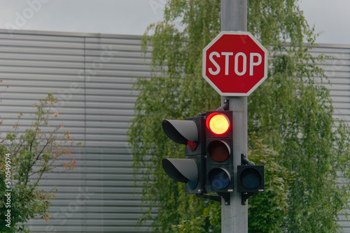 Stop street sign and red traffic light attached to a metal pole 