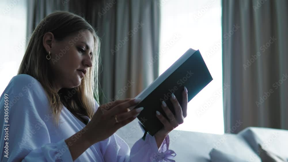 Woman reading book near window. Hand turns book pages. Self education concept. Pretty female girl holding a book reading a bible. Freelancer having a rest at home reading literature Woman reading book near window. Hand turns book pages. Self education concept. Pretty female girl holding a book reading a bible. Freelancer having a rest at home reading literature