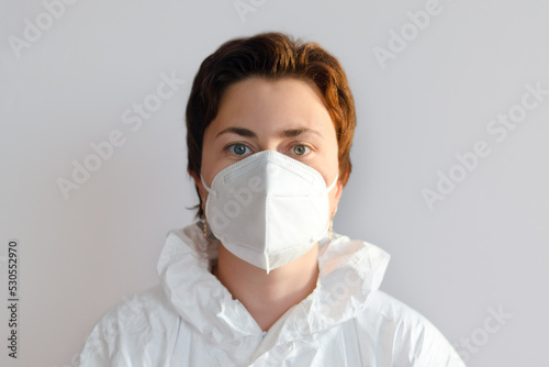 Portrait of professional confident young doctor in a medical mask, white coat. White background. Top view of syringe and vaccine vial glass bottle for vaccination COVID-19. Coronavirus pandemic