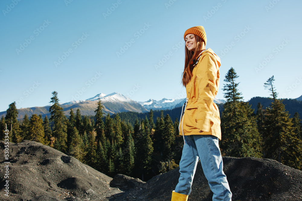 Woman smile with teeth happiness and laughter hiker in yellow raincoat put her hands up and jumping trip in the fall and hiking in the mountains in the sunset freedom