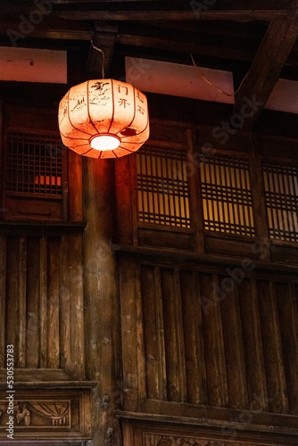 Vertical shot of a Japanese lantern hang near a wooden door photo