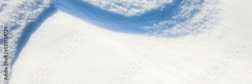 Beautiful winter background with snowy ground. Natural snow texture. Wind sculpted patterns on snow surface. Wide panoramic texture for background and design. Closeup top view with copy space. © Andrei Stepanov