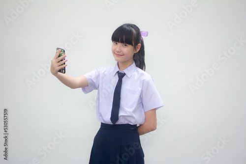 Portrait of thai Junior high school student uniform beautiful girl using her smart phone Selfie