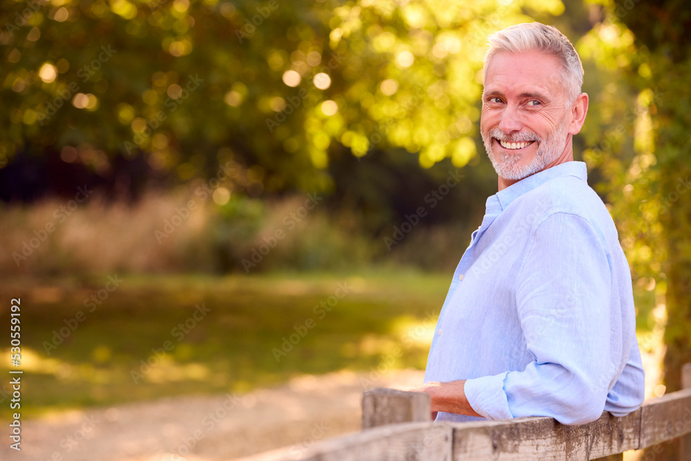 Casually Dressed Mature Man Leaning On Fence On Walk In Countryside Casually Dressed Mature Man Leaning On Fence On Walk In Countryside