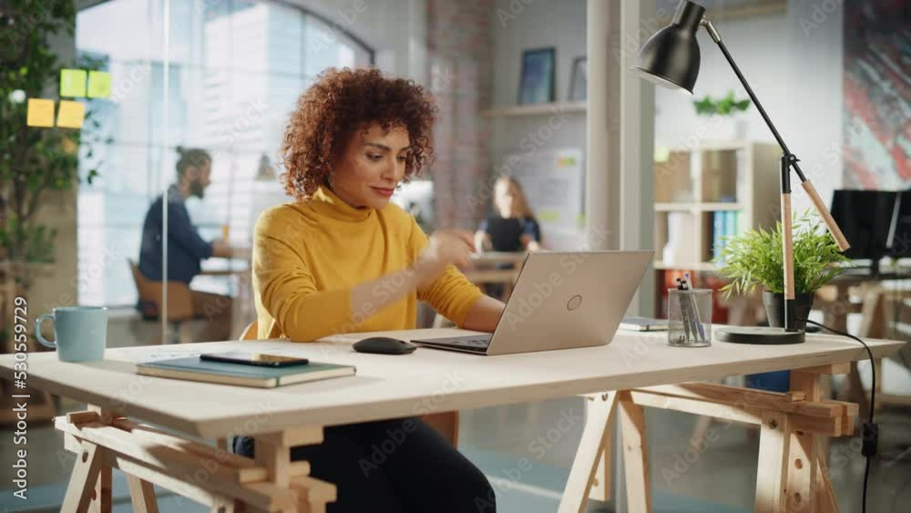 Confident Arab Female Sitting in Creative Agency, Manager Working on Implementing Modern Business Strategy for Client. Excited Specialist Writing Corporate Project Plans on Laptop Computer.