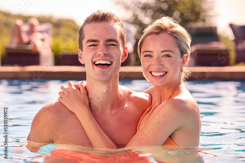 Portrait Of Smiling Couple On Summer Holiday Relaxing In Swimming Pool
