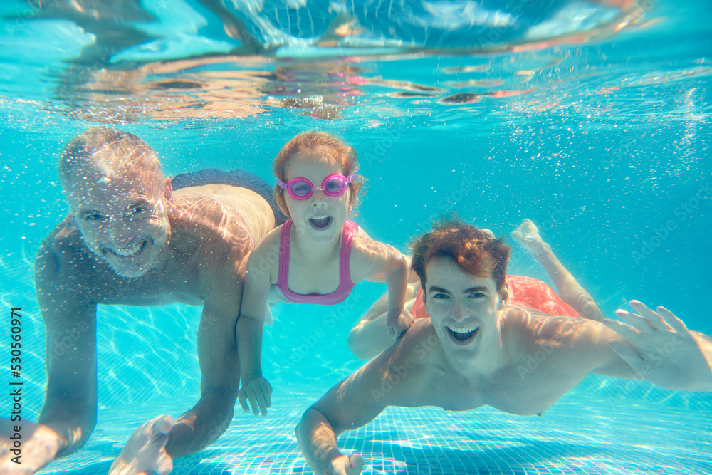 Portrait Of Multi-Generation Family On Summer Holiday Swimming Underwater In Pool