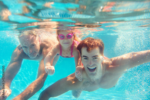 Portrait Of Multi-Generation Family On Summer Holiday Swimming Underwater In Pool © Monkey Business
