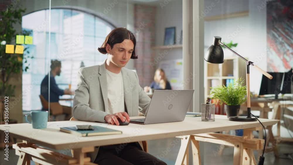 Creative Project Manager Sitting at a Desk, Working on a Laptop Computer in an Office. Handsome Marketing Specialist in a Casual Jacket Planning a Project, Browsing Internet and Writing Emails. Creative Project Manager Sitting at a Desk, Working on a Laptop Computer in an Office. Handsome Marketing Specialist in a Casual Jacket Planning a Project, Browsing Internet and Writing Emails.