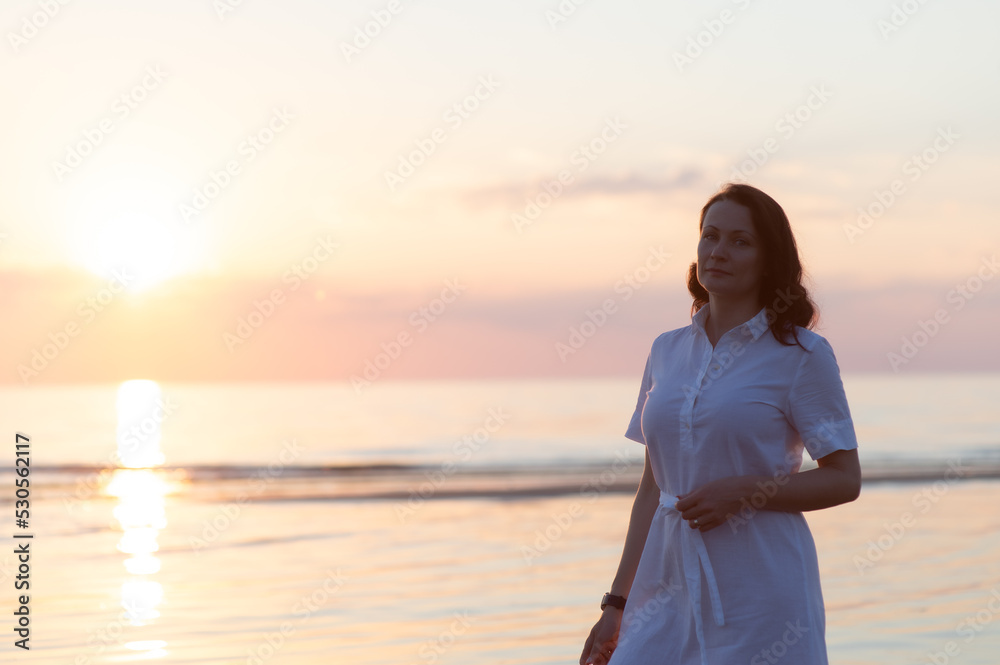 Pretty mature woman stands on the beach and looks thoughtfully at camera Pretty mature woman stands on the beach and looks thoughtfully at camera
