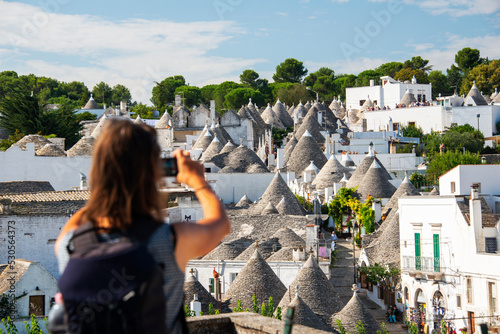 Beautiful tourist woman looking Alberobello old town from a balcony, Italy 