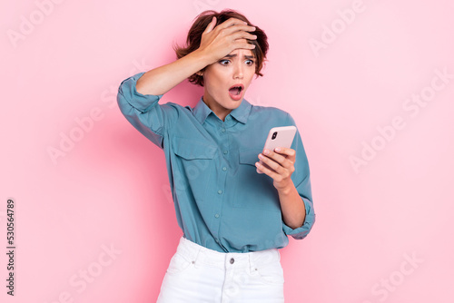 Photo of young attractive cute woman wear stylish blue shirt touch forehead shocked speechless bad comment facebook isolated on pink color background
