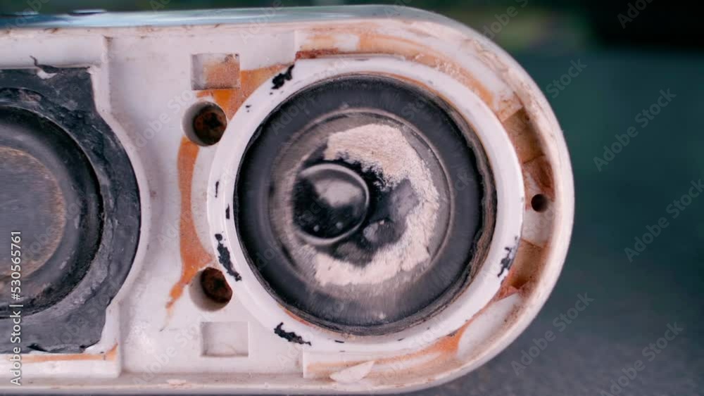 An old broken speaker with a dented diffuser plays very loudly. Loud listening to music. Broken wireless speaker loses bass close-up An old broken speaker with a dented diffuser plays very loudly. Loud listening to music. Broken wireless speaker loses bass close-up