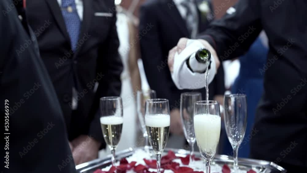 Professional waiter pouring champagne on drinking glasses over a silver tray on a wedding celebration. Professional waiter pouring champagne on drinking glasses over a silver tray on a wedding celebration.