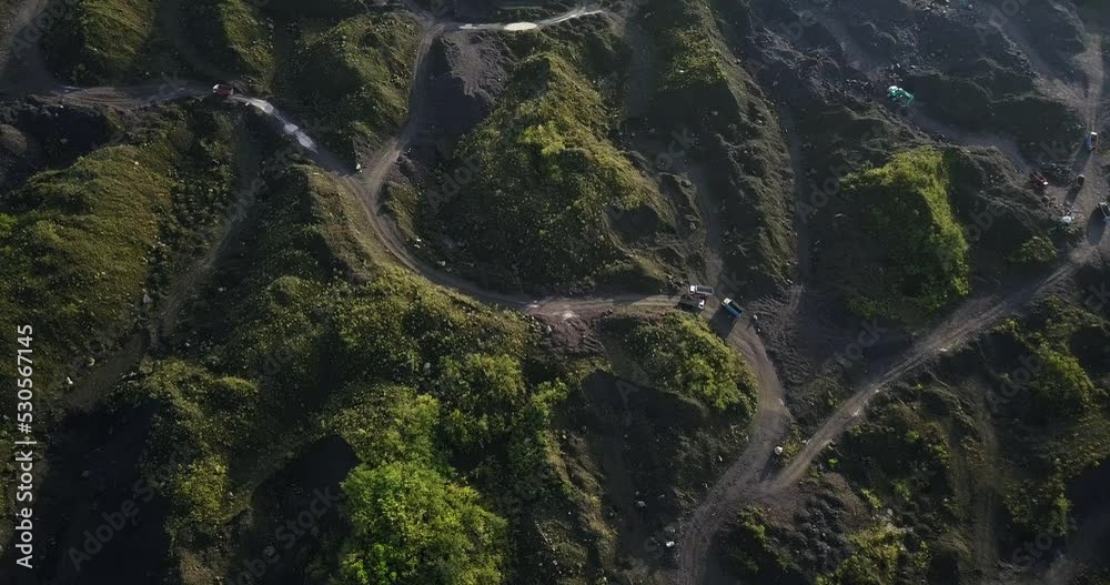 Drone shot of activity on the mine site. Trucks loading sand and driving along sand mine, Moving trucks on the sand mine - View of environmental damage due to mining activities
