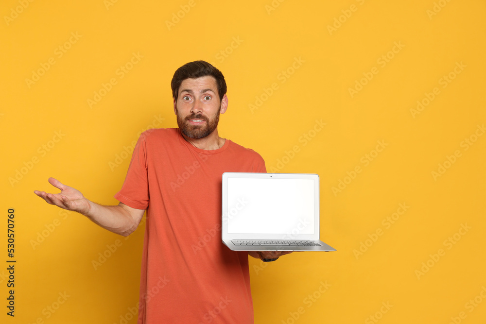 Handsome man with laptop on orange background Handsome man with laptop on orange background