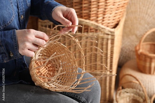 Woman weaving wicker basket indoors, closeup view