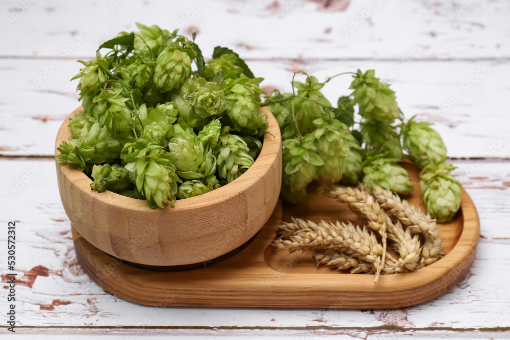 Fresh green hops and ears of wheat on white wooden table, closeup Fresh green hops and ears of wheat on white wooden table, closeup
