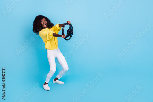 Full size body photo of young crazy woman holding car steering wheel test drive isolated on blue color background