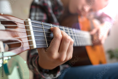 Fingers of a child playing the guitar. Girl playing guitar at home.