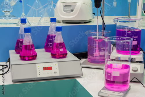 Magnetic mixer stirrers with fast moving stir bar for mixing purple liquid at medical factory, exhibition, trade show: close up. Chemistry, science, pharmaceutical, laboratory equipment concept photo