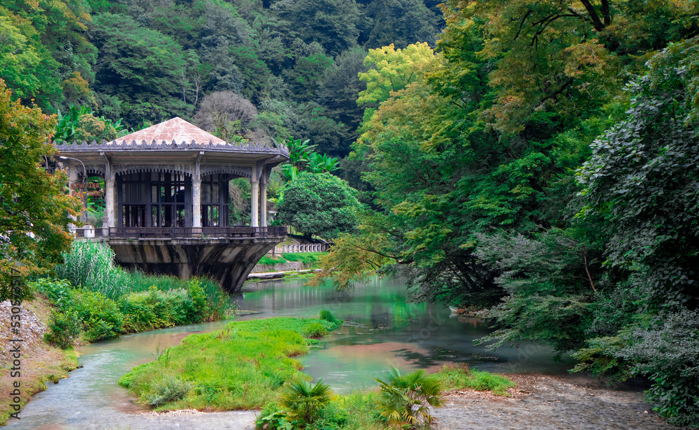 Abkhazia, New Athos - July 31, 2022.Picturesque abandoned Psyrtskha railway station against the background of green trees and turquoise water. The concept of travel and historical attractions