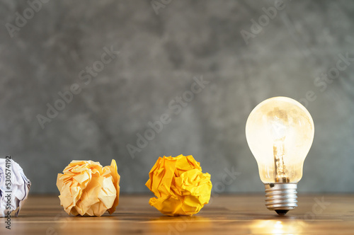Close up photo of crumbled colorful paper and light bulb in the same frame as a symbol of persistance, perseverance and hardwork. Concept of creative idea , brainstorm and innovative thinking.