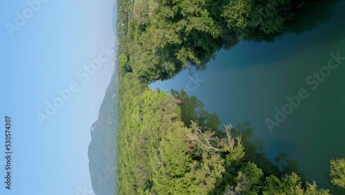 Drone vertical shot of tranquil Rio Munoz River in Puerto Plata at sunny day and blue sky - Beautiful mountain in background - Puerto Plata,DOminican Republic photo
