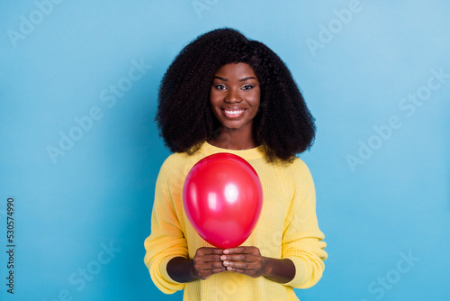 Photo of nice gorgeous pretty girl with wavy hair dressed yellow sweater holding balloon prepare holiday isolated on blue color background © deagreez